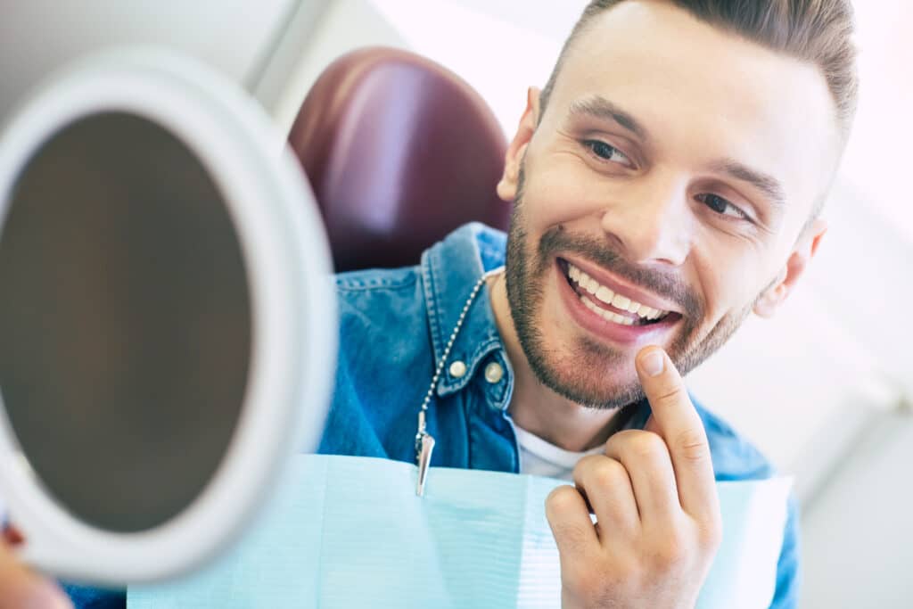 espejo mano hombre atractivo sonrisa perfecta que usando comprobar aspecto final su sonrisa